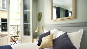 Une chambre à coucher avec un lit, des oreillers, une table de chevet, une lampe et un miroir.