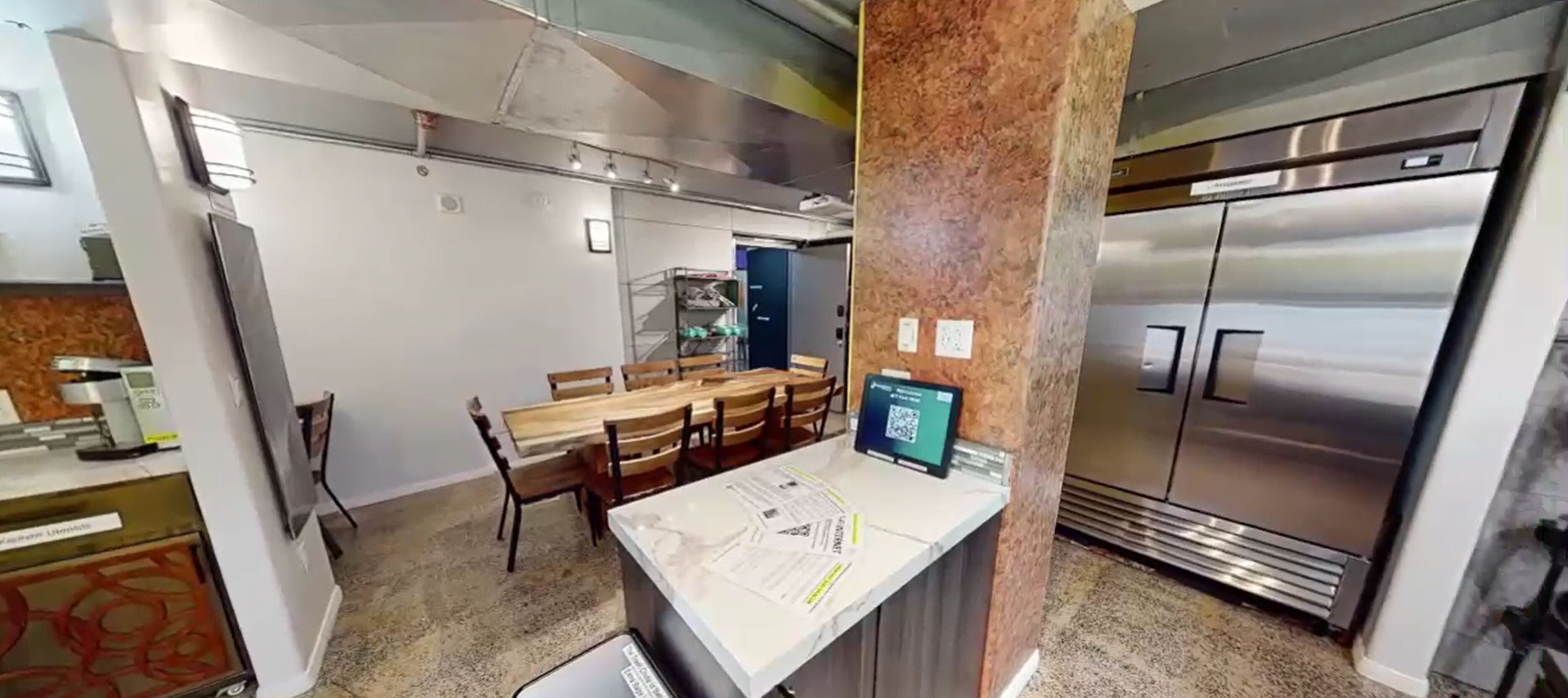 Une cuisine moderne dotée d’appareils électroménagers en acier inoxydable, d’un plan de travail en marbre et d’un coin repas avec des chaises en bois.