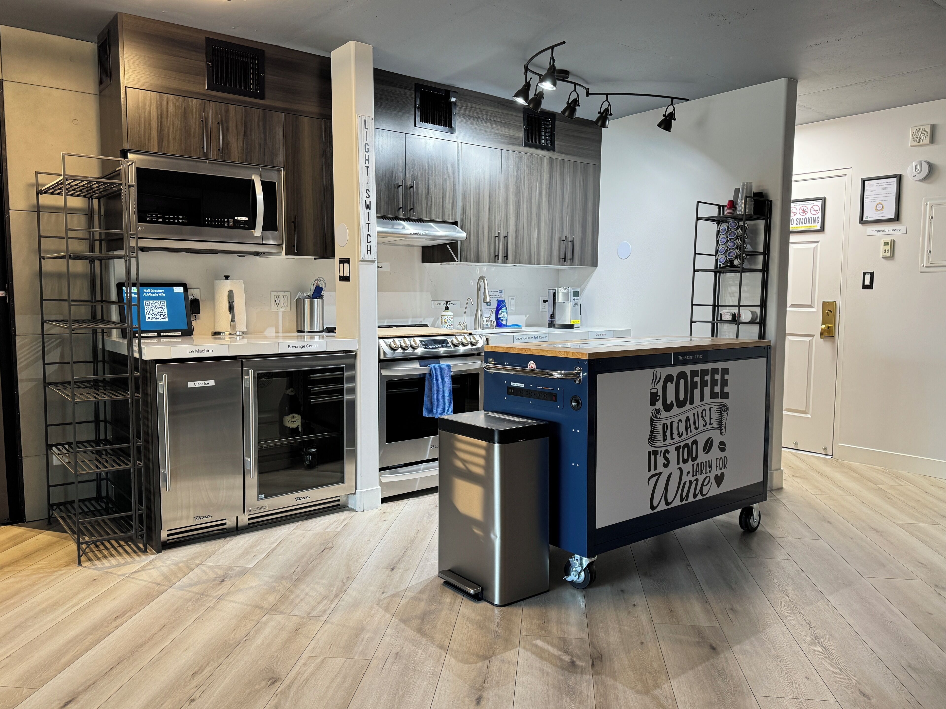 A modern kitchen with stainless steel appliances, a coffee station, and a clear glass door oven.