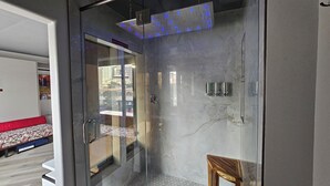 A modern bathroom with a glass shower enclosure, a marble wall, and a visible cityscape through the glass door. - LVStripHouse Condos Sleeps up to 14 (Las Vegas)