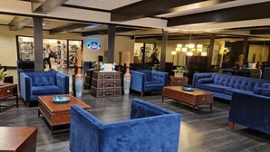 A spacious lobby with blue sofas and armchairs, wooden coffee tables, and a large mirror.