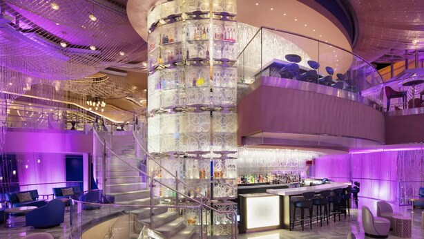 A modern hotel lobby with a central spiral staircase, a bar area, and seating arrangements.
