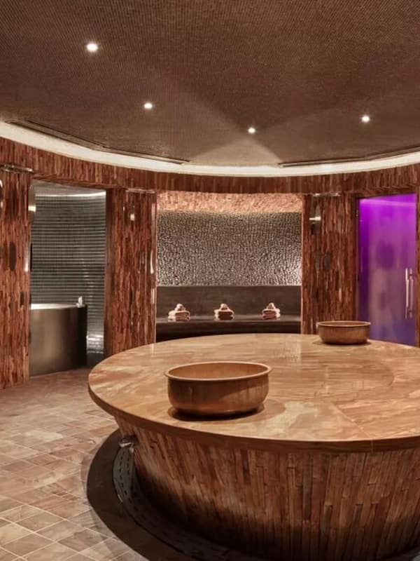 Relax in a serene spa area with a central hot tub, lounge chairs, and a stone basin.