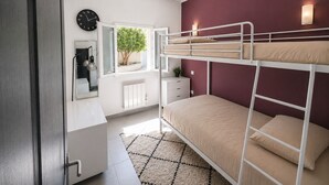 A bunk bed room with a white dresser, a mirror, a clock, and a window with a view of a tree. - La Perla di Santa Maria - Vue mer, plage à 100 m (Santa-Maria-Poggio)
