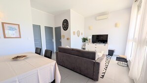 A modern living room with a sofa, dining table, and a TV. - La Perla di Santa Maria - Vue mer, plage à 100 m (Santa-Maria-Poggio)