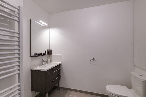 A modern bathroom with a white sink, dark vanity, and a toilet.