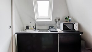 Une petite cuisine équipée d’un four à micro-ondes, d’une bouilloire et d’un petit évier.