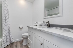 A bathroom with a white sink, toilet, and shower curtain. - New Remodeled 1BR/1BA in DT Tacoma - 1 (Tacoma)
