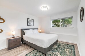 A bedroom with a bed, bedside tables, a window, and a view of the outdoors. - New Remodeled 1BR/1BA in DT Tacoma - 1 (Tacoma)