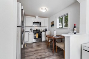 A compact kitchen with modern appliances, a dining area with a table and chairs, and a window with a view of the outside. - New Remodeled 1BR/1BA in DT Tacoma - 1 (Tacoma)