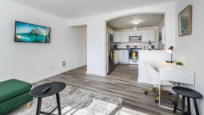 A modern apartment with a kitchen, dining area, and a green sofa.