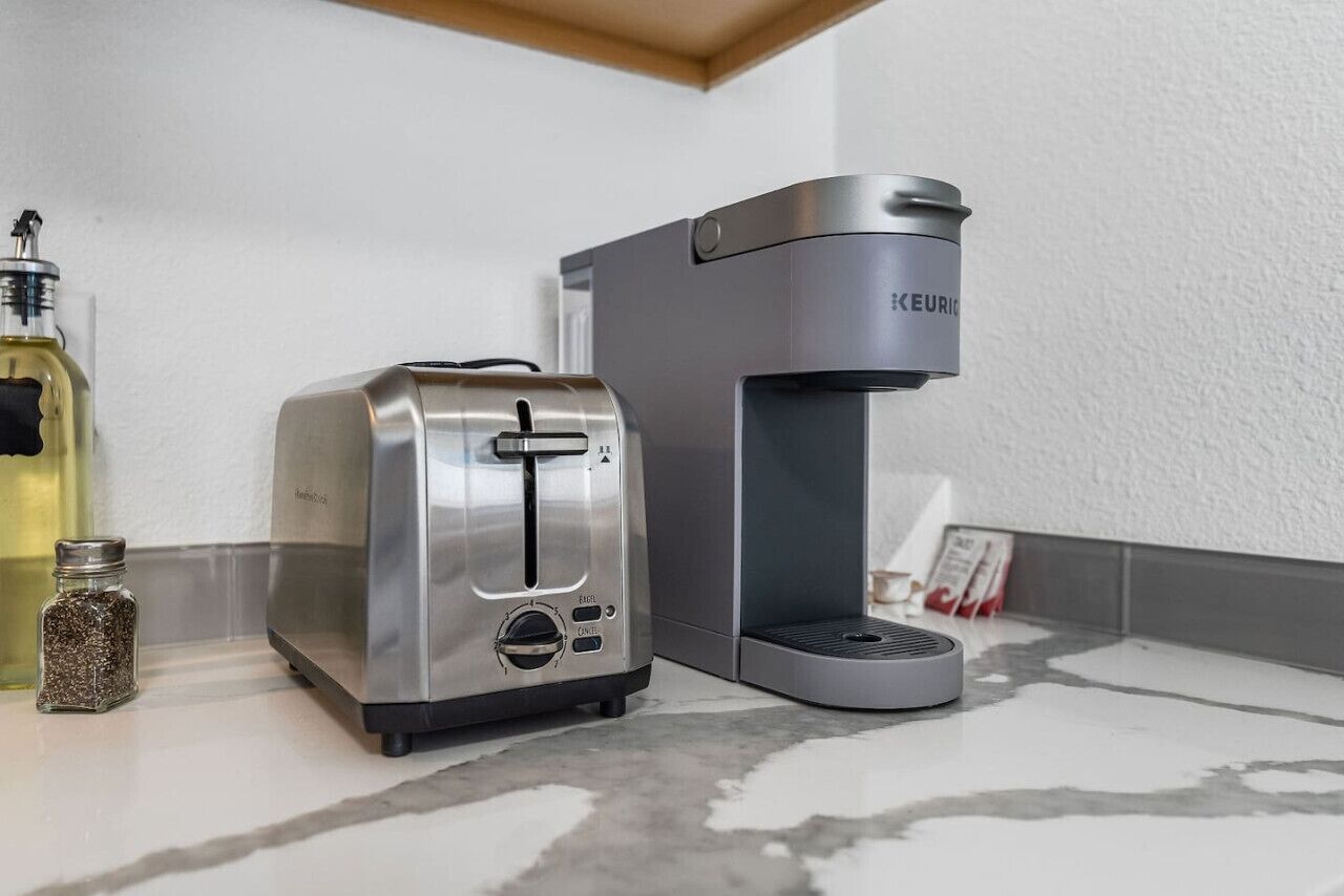 Una cocina con un tostador y una cafetera sobre una encimera de mármol.