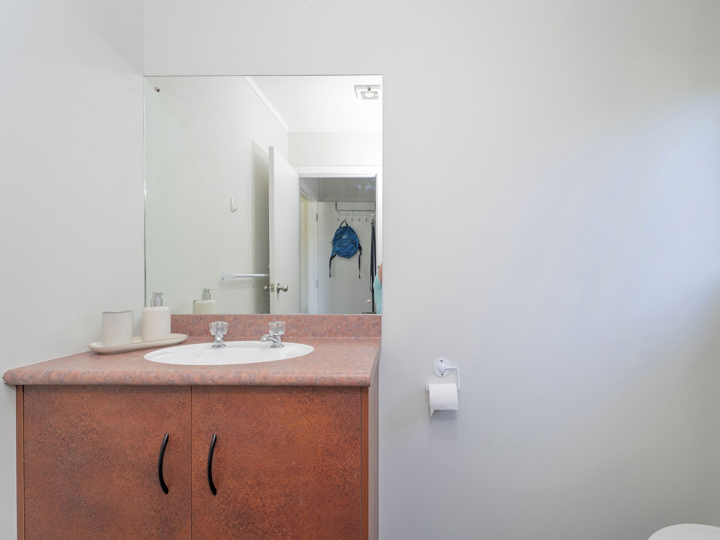 A bathroom with a white sink, a mirror, and a towel dispenser.