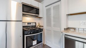 A compact kitchen with a stainless steel refrigerator, a microwave, a gas stove, and a dishwasher. - Lovely Remodeled 1BR in DT Tacoma - 6 (Tacoma)
