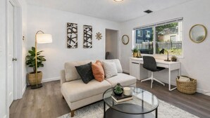 A living room with a sofa, coffee table, desk, and a large window. - Lovely Remodeled 1BR in DT Tacoma - 6 (Tacoma)