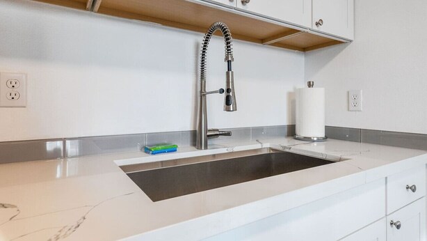 A modern kitchen with a stainless steel sink, white cabinets, and a wooden countertop. - Lovely Remodeled 1BR in DT Tacoma - 6 (Tacoma)