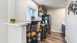 A compact kitchen with a bar area, a stove, and a microwave.