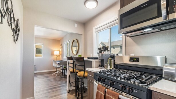 A modern kitchen with a gas stove, stainless steel appliances, and a dining area with a table and chairs.