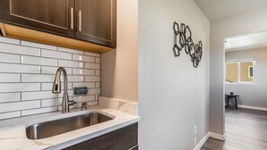 A kitchen with a stainless steel sink, dark wooden cabinets, and white subway tiles.