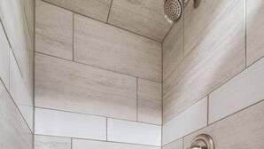 A shower with a tiled wall and a showerhead.