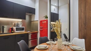 A modern kitchen with dark cabinets, a red refrigerator, and a dining area with a wooden table set for four.