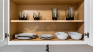 A cabinet with two shelves, each holding plates and glasses.