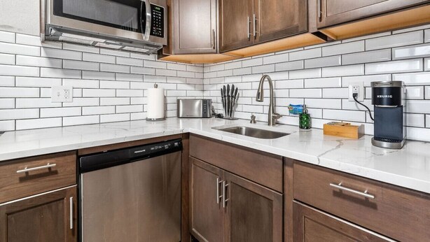 A modern kitchen with stainless steel appliances, wooden cabinets, and white subway tiles.