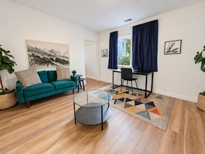 Een woonkamer met een bank, salontafel en een eethoek met stoelen en een tafel.