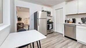 A compact kitchen with white cabinets, a stainless steel refrigerator, a microwave, an oven, and a dishwasher.