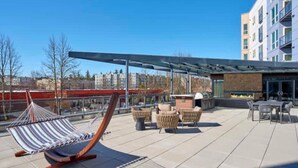 Terraza en la azotea con una hamaca, mobiliario de mimbre y una chimenea.
