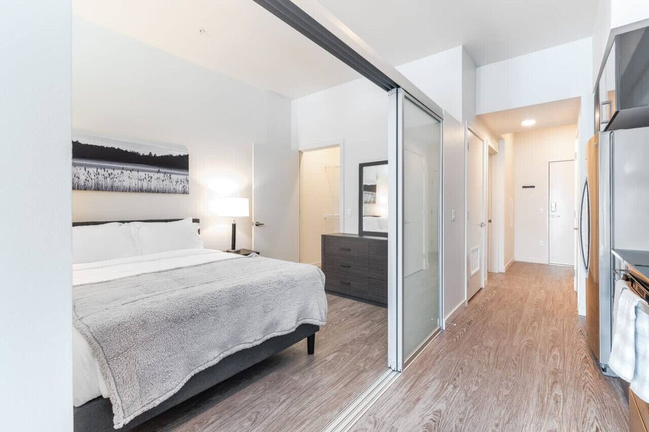 Een moderne slaapkamer met een bed, een dressoir en een schuifdeur naar een badkamer.