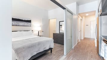 Een moderne slaapkamer met een bed, een dressoir en een schuifdeur naar een badkamer.