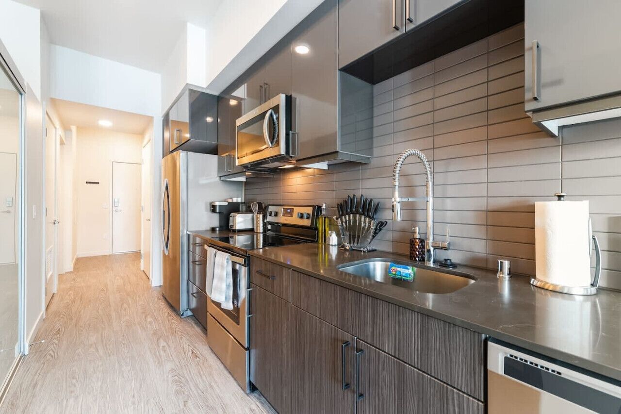 Een moderne keuken met roestvrijstalen apparatuur, een groot eiland met een spoelbak en houten kasten.