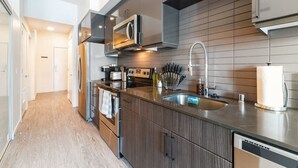 Una cocina moderna con electrodomésticos de acero inoxidable, una isla grande con pileta y muebles de madera.