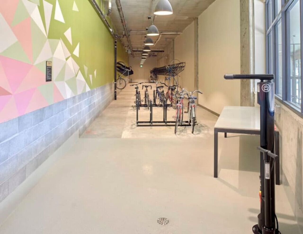 A hallway with bicycles parked against the wall, a table, and a wall with geometric patterns.