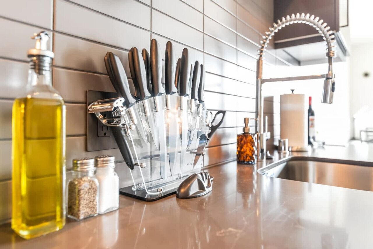 A kitchen with a knife block, a bottle of oil, and a salt shaker on the counter.