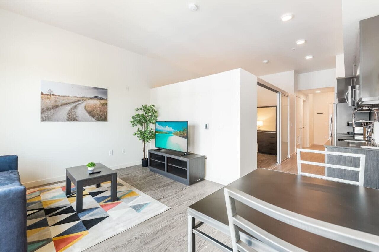 A modern living room with a sofa, coffee table, TV, and a painting on the wall.