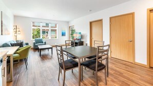 Ein modernes Wohnzimmer mit Essbereich, Holzböden und großen Fenstern.