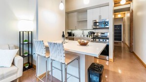 A modern kitchen with white cabinets, stainless steel appliances, and a central island with bar stools.