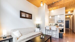 A modern living room with a sofa, coffee table, and a kitchen area with a microwave and stove.
