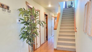 A hallway with a wooden bench, a potted plant, and a staircase leading to another room.