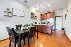 A modern kitchen with wooden cabinets, a central island, and a dining area with a dark wooden table and chairs.