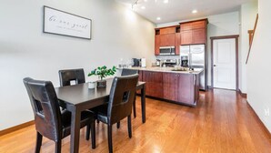 A modern kitchen with wooden cabinets, a central island, and a dining area with a dark wooden table and chairs.