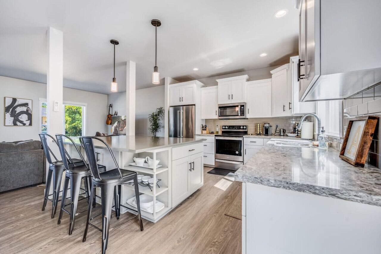 A modern kitchen with white cabinetry, stainless steel appliances, and a marble countertop.