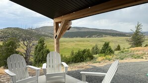 Un espace extérieur aménagé, abrité et doté de deux fauteuils Adirondack et d’une pergola en bois.