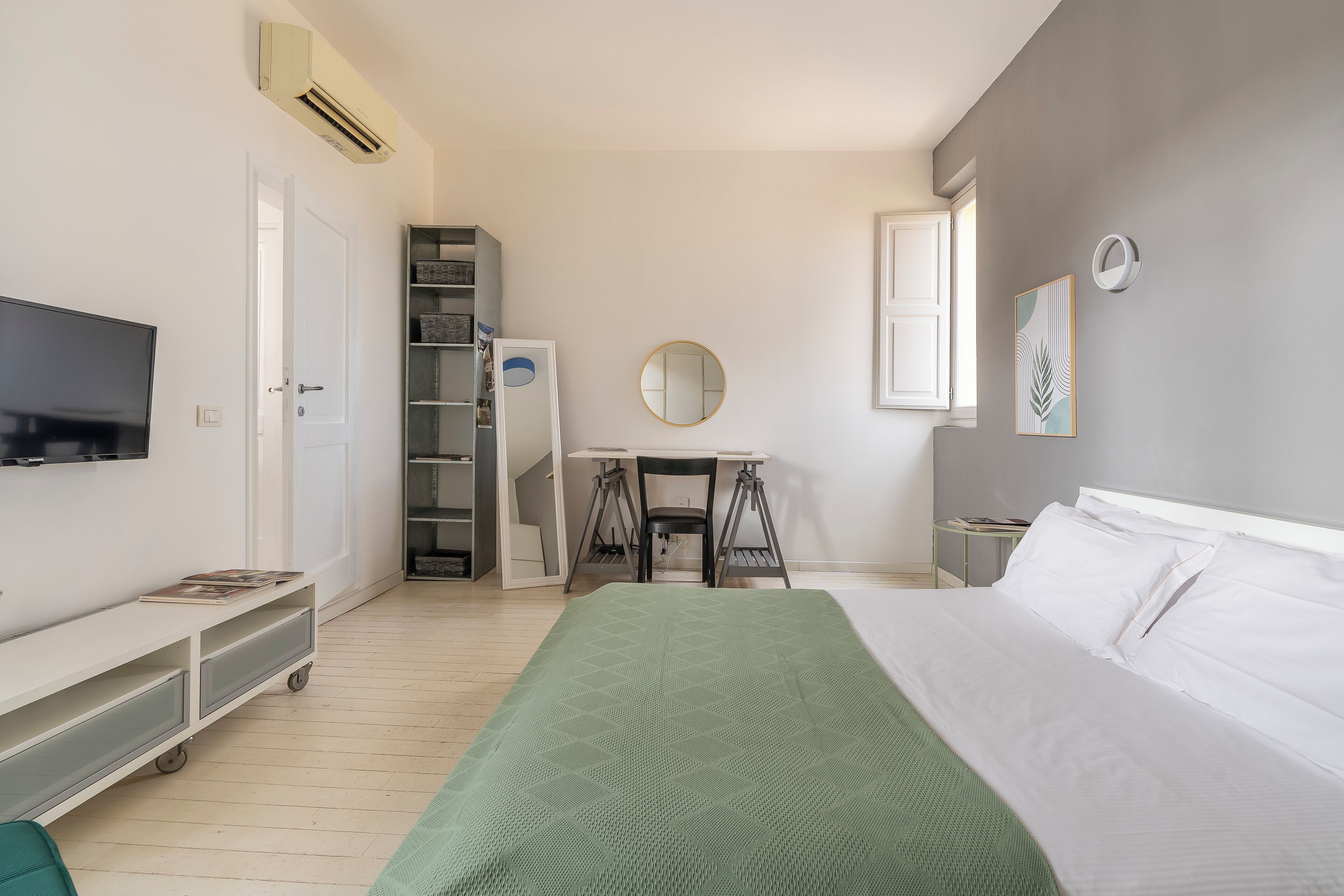 A bedroom with a bed, a desk, a chair, a TV, and a wardrobe.