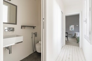 Kylpyhuone, jossa on valkoinen pesuallas, peili, suihku ja wc.