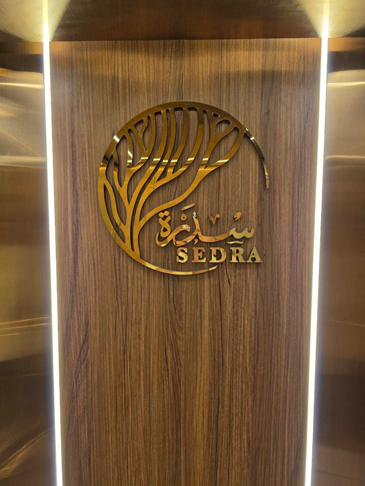 Ein Holzausschild mit einem goldenen Logo und der eingravierten Aufschrift "SEDRA".