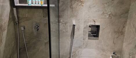 Moderni kylpyhuone, jossa on lasiseinällä varustettu suihku, wc ja pesuallas.
