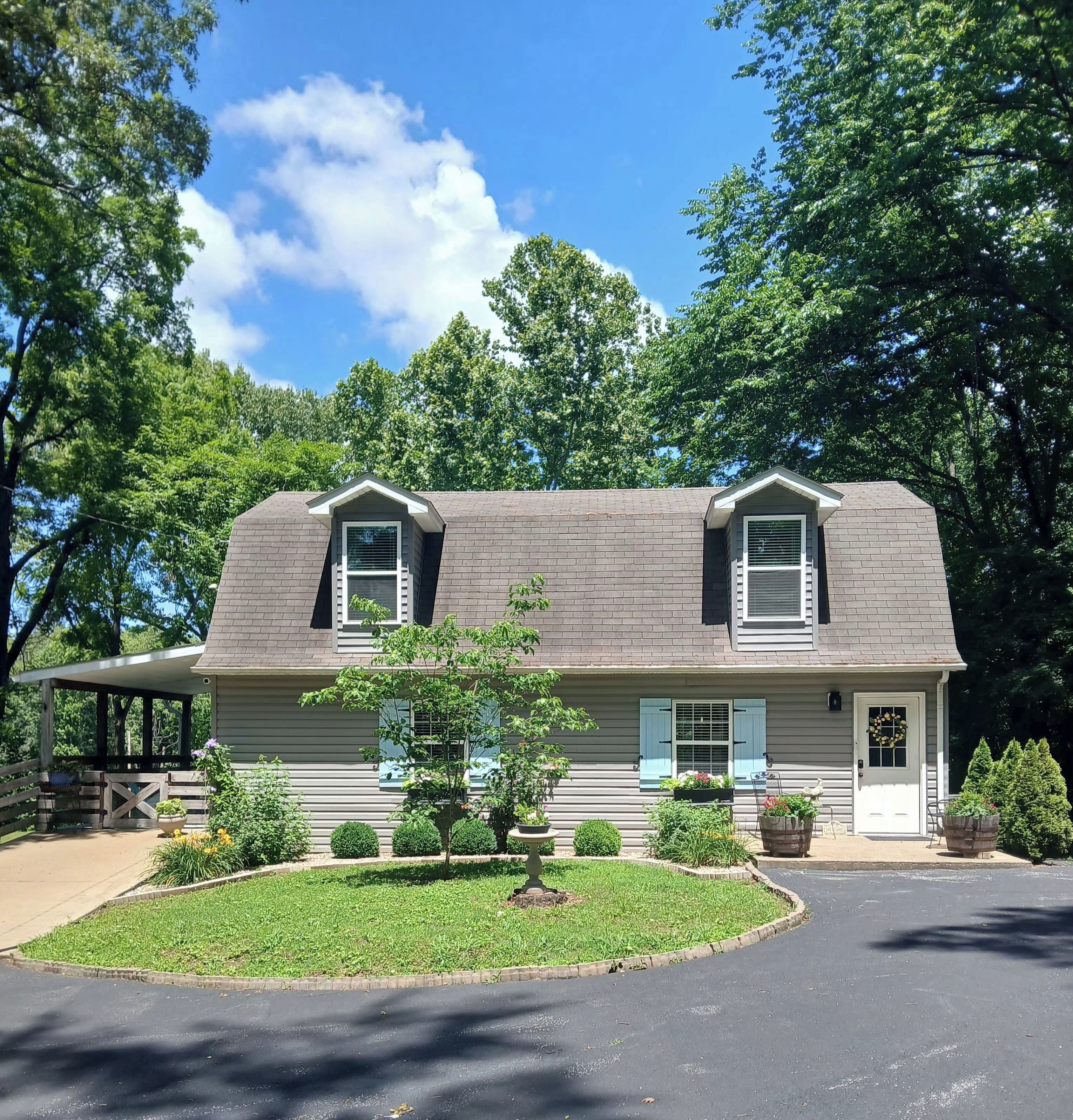 A two-story house with a covered porch, a front yard with a small tree, and a driveway.